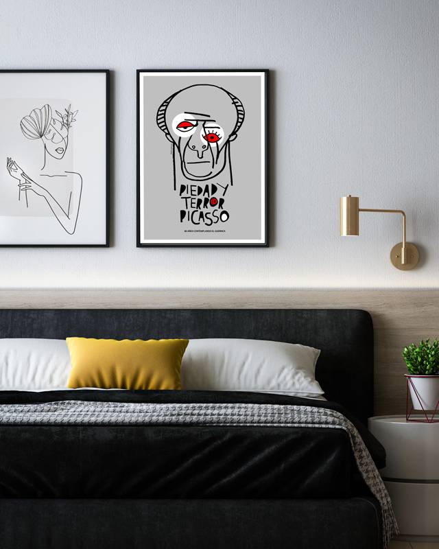 The minimalist graphic depicts Picasso’s face with red accent eyes, referencing the emotional power of ‘Guernica’. Displayed above a modern bed with monochrome bedding and a yellow accent pillow