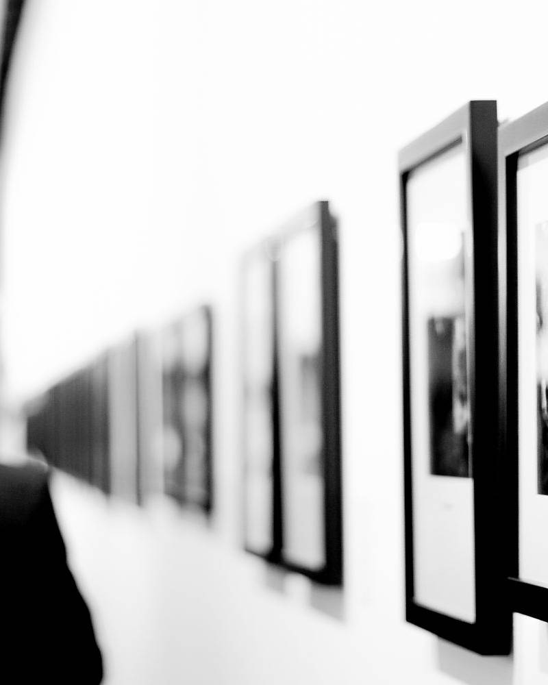 Visitors viewing a contemporary photography exhibition featuring framed black-and-white prints in a minimalist gallery setting